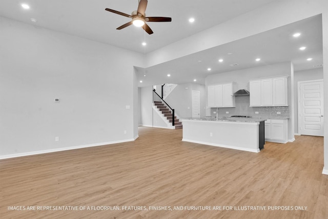 kitchen with white cabinetry, decorative backsplash, open floor plan, and light wood-type flooring