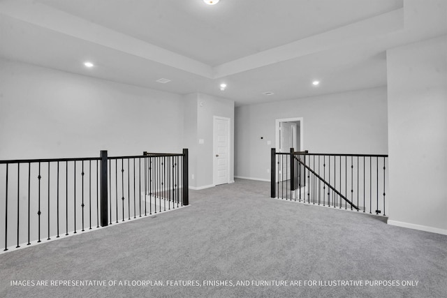 carpeted spare room with recessed lighting, baseboards, and a raised ceiling