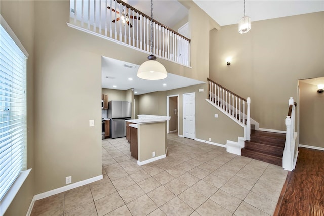 kitchen featuring light tile patterned floors, stainless steel appliances, a healthy amount of sunlight, and a high ceiling