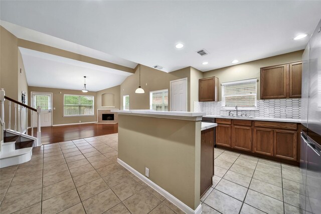 kitchen with sink, hanging light fixtures, light tile patterned flooring, decorative backsplash, and vaulted ceiling