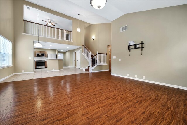 unfurnished living room featuring ceiling fan, lofted ceiling, and light hardwood / wood-style floors