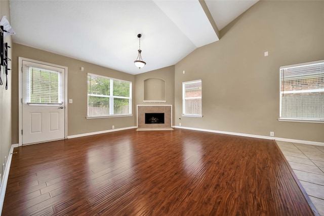 unfurnished living room featuring a tile fireplace, lofted ceiling, and dark wood-type flooring