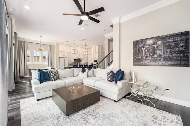 living room featuring hardwood / wood-style flooring, ceiling fan with notable chandelier, and ornamental molding