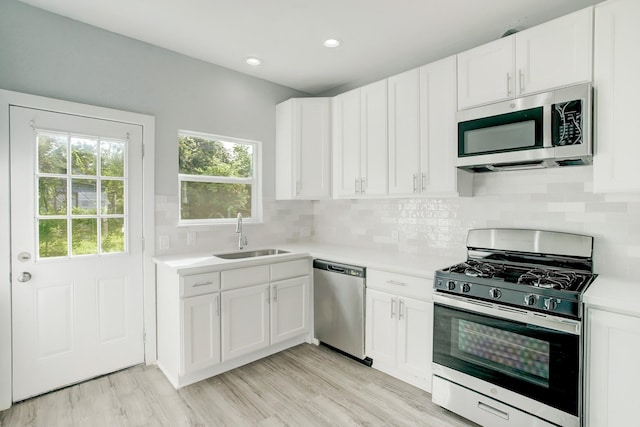 kitchen featuring sink, backsplash, stainless steel appliances, and white cabinets