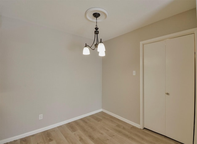 unfurnished dining area with an inviting chandelier and light hardwood / wood-style flooring