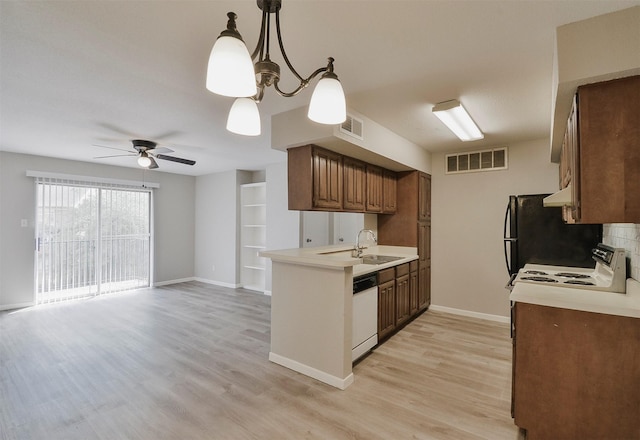 kitchen featuring sink, hanging light fixtures, light hardwood / wood-style flooring, range with electric stovetop, and white dishwasher