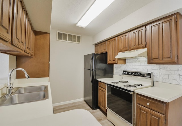 kitchen with electric stove, sink, tasteful backsplash, light hardwood / wood-style floors, and black fridge