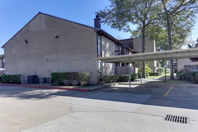 back of house with a carport and central AC