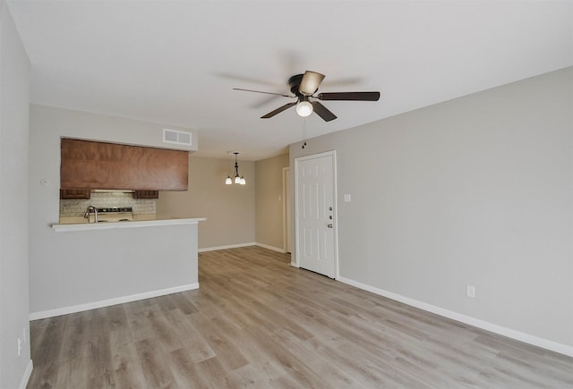 unfurnished living room featuring ceiling fan with notable chandelier, sink, and light hardwood / wood-style floors