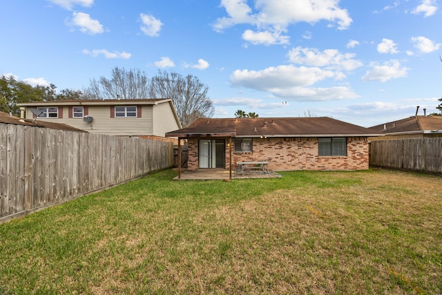 rear view of property featuring a fenced backyard, a lawn, brick siding, and a patio