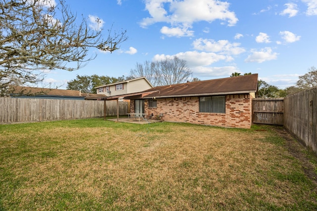 back of property featuring a yard, brick siding, a patio, and a fenced backyard