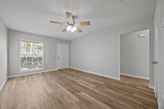 empty room with ceiling fan, wood finished floors, and baseboards