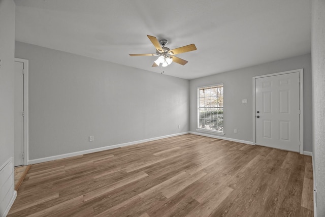 empty room with ceiling fan, wood finished floors, and baseboards