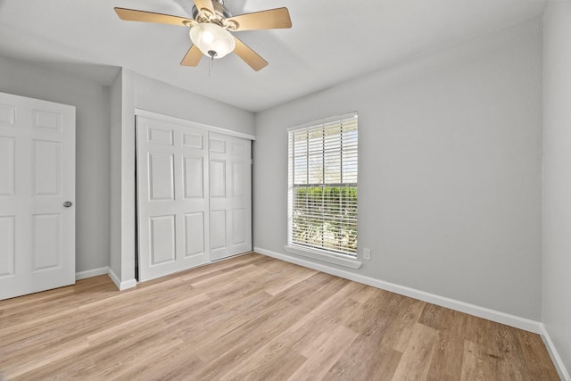 unfurnished bedroom featuring light wood-style floors, a closet, baseboards, and a ceiling fan