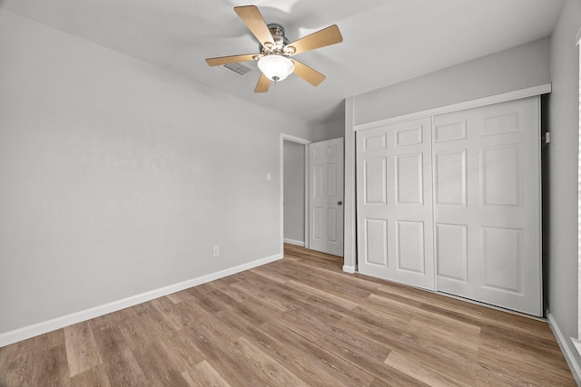 unfurnished bedroom featuring light wood-style flooring, baseboards, a closet, and a ceiling fan
