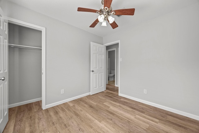 unfurnished bedroom featuring light wood-style floors, ceiling fan, baseboards, and a closet