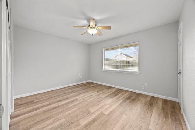 empty room with ceiling fan, light wood-style floors, and baseboards