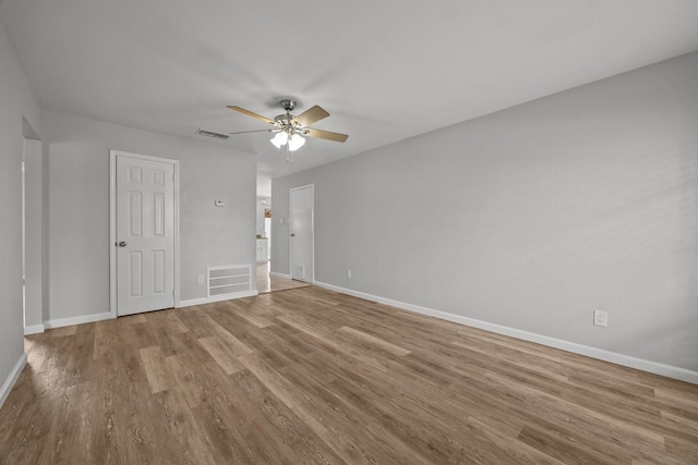 empty room featuring visible vents, ceiling fan, baseboards, and wood finished floors