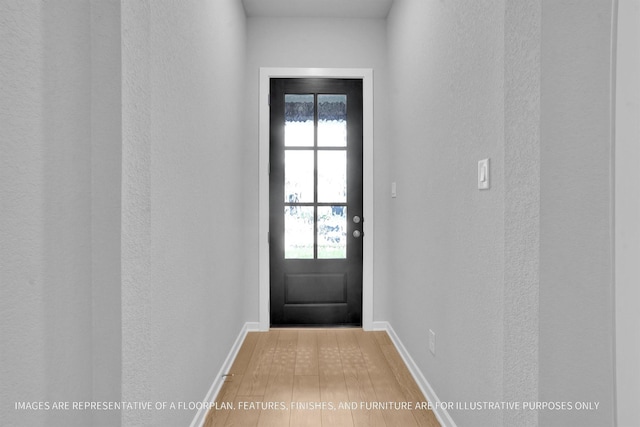 doorway featuring baseboards and light wood-type flooring