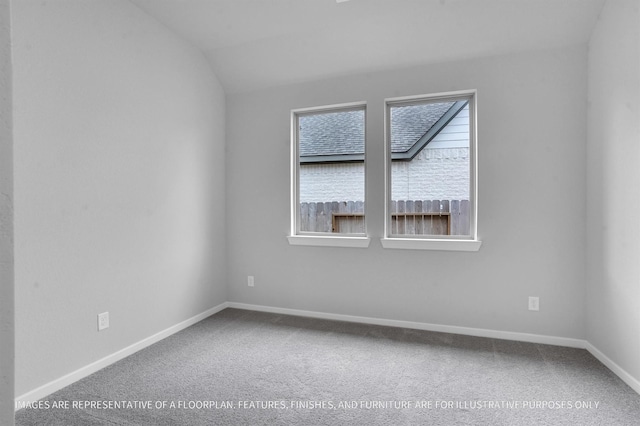 carpeted empty room featuring baseboards and vaulted ceiling