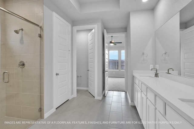 bathroom featuring baseboards, double vanity, a stall shower, a sink, and tile patterned flooring