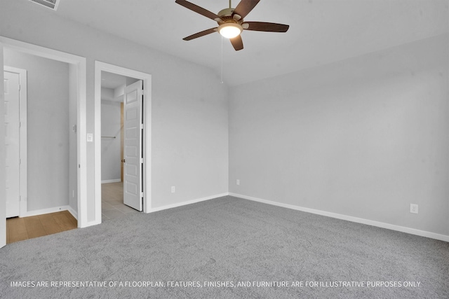 unfurnished bedroom with a walk in closet, visible vents, carpet flooring, baseboards, and ceiling fan