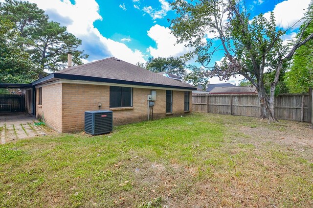 rear view of property featuring central AC and a lawn