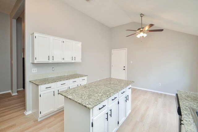 kitchen featuring white cabinets, a center island, ceiling fan, light stone countertops, and light hardwood / wood-style flooring