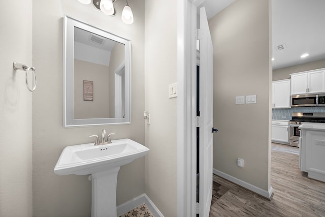 bathroom with hardwood / wood-style floors and backsplash