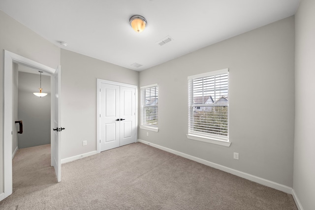 unfurnished bedroom with light colored carpet and a closet