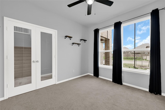 carpeted spare room featuring plenty of natural light, ceiling fan, and french doors