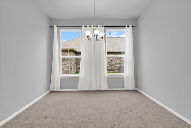 empty room featuring a chandelier and carpet