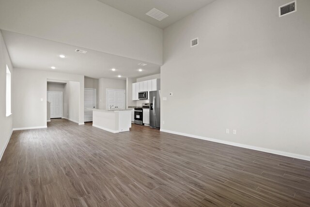 unfurnished living room with recessed lighting, visible vents, baseboards, and dark wood-style floors