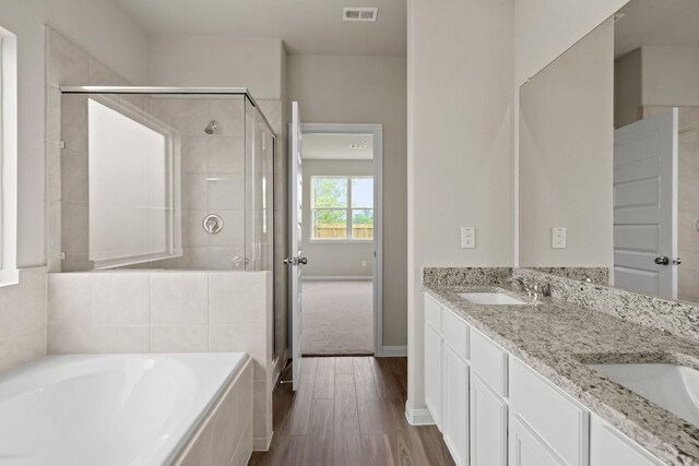 bathroom featuring a stall shower, a garden tub, a sink, and visible vents