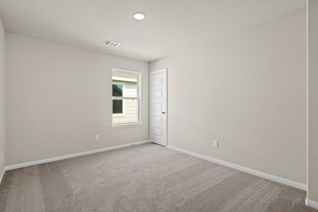 empty room with recessed lighting, visible vents, light colored carpet, and baseboards