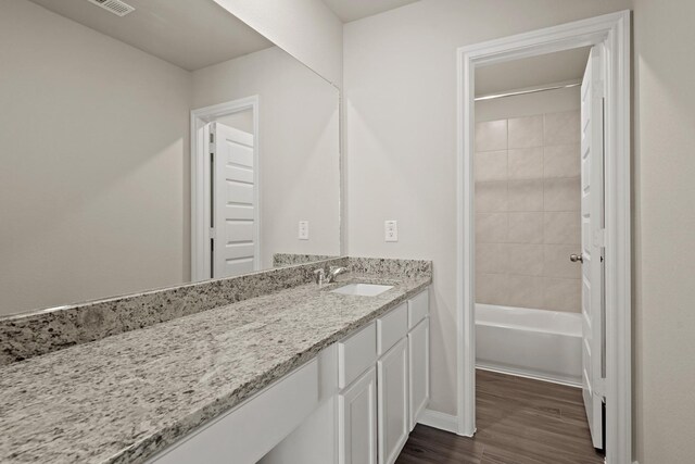 full bath featuring washtub / shower combination, vanity, and wood finished floors