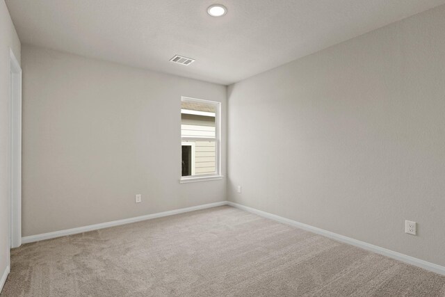 carpeted empty room with visible vents and baseboards