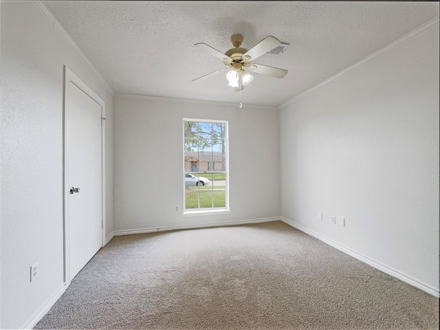 empty room with ornamental molding, carpet, ceiling fan, and a textured ceiling