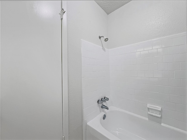 bathroom featuring tiled shower / bath combo and a textured ceiling