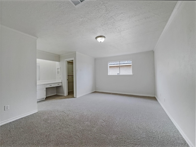 unfurnished bedroom featuring crown molding, built in desk, light carpet, and a textured ceiling