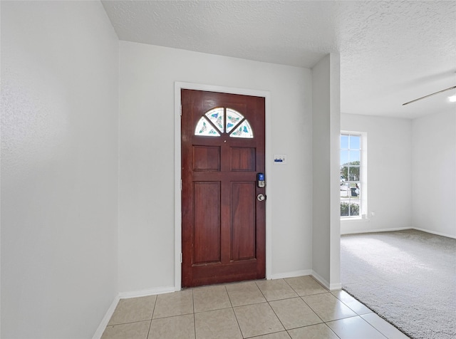 tiled entrance foyer with ceiling fan and a textured ceiling