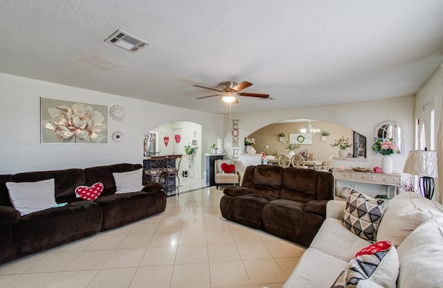 living room with ceiling fan with notable chandelier, a textured ceiling, and light tile patterned floors