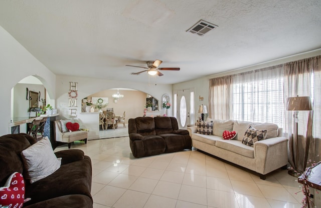 living room featuring light tile patterned floors, ceiling fan with notable chandelier, and a textured ceiling