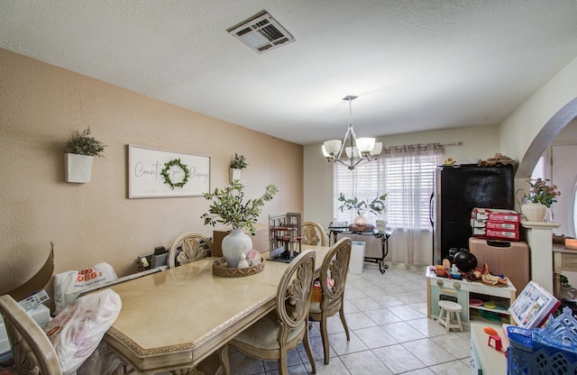 dining room with light tile patterned flooring, a notable chandelier, and a textured ceiling