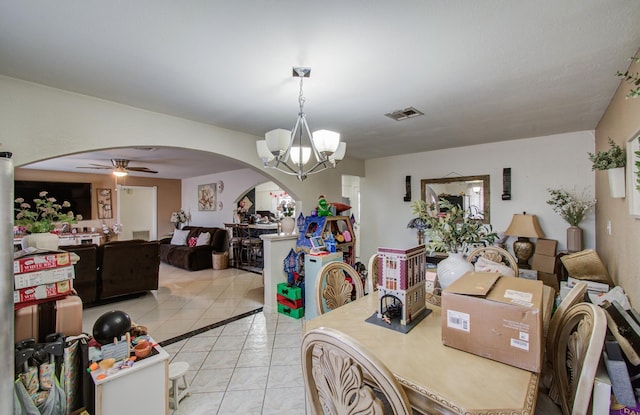 tiled dining room with ceiling fan with notable chandelier