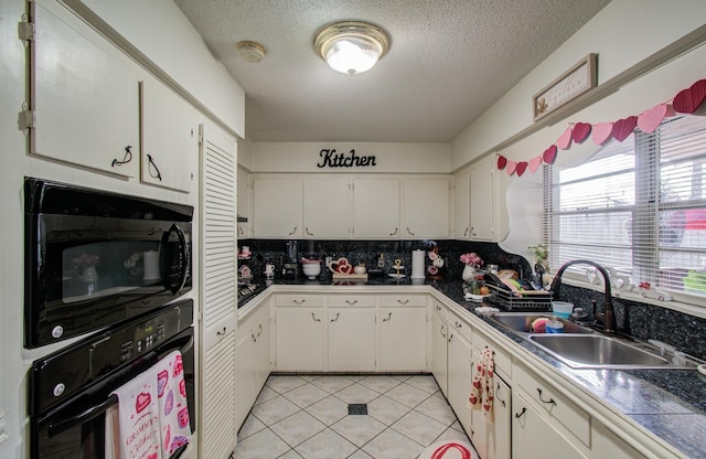 kitchen with sink, black appliances, a textured ceiling, light tile patterned floors, and white cabinets