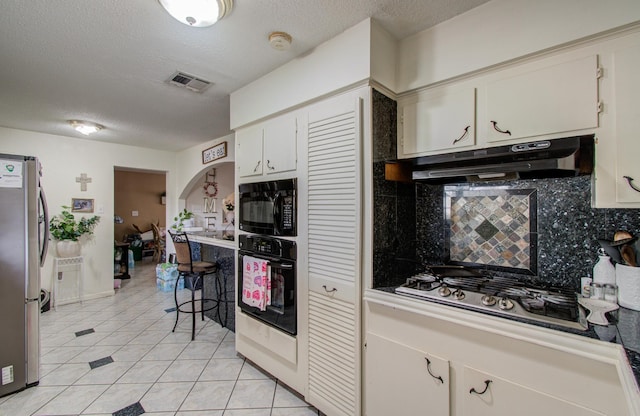 kitchen featuring light tile patterned floors, white cabinetry, tasteful backsplash, black appliances, and a textured ceiling