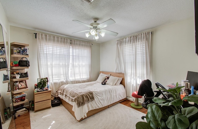 bedroom featuring ceiling fan, a textured ceiling, and light hardwood / wood-style flooring