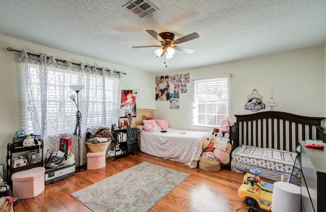 bedroom featuring ceiling fan, hardwood / wood-style floors, and a textured ceiling