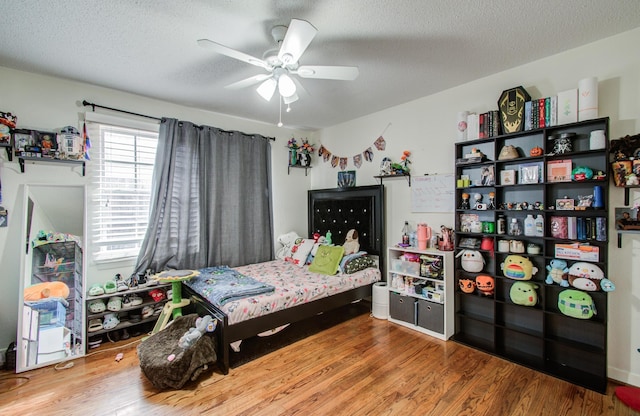 bedroom featuring wood-type flooring, ceiling fan, and a textured ceiling